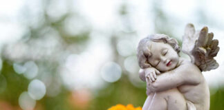 A cherub statue resting beside a bright orange flower