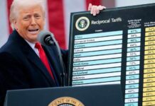A politician speaking at a podium while holding a chart on reciprocal tariffs