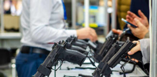 Display of handguns at a firearms exhibition with attendees interacting
