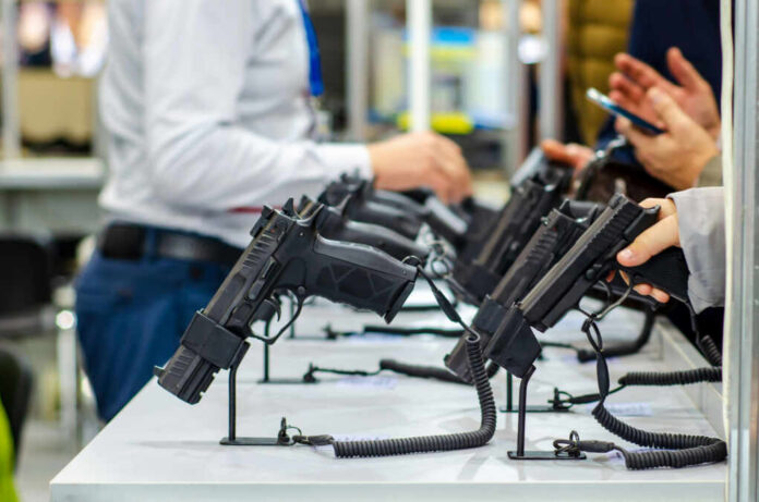 Display of handguns at a firearms exhibition with attendees interacting