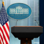 BREAKING: Gunfire Chaos Strikes White House Podium with microphones in front of the White House seal and an American flag
