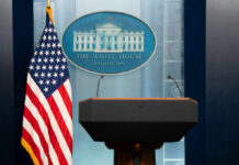 BREAKING: Gunfire Chaos Strikes White House Podium with microphones in front of the White House seal and an American flag