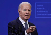 A speaker addressing an audience at a conference with a serious expression