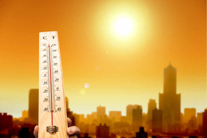 A thermometer held against a sunset city skyline