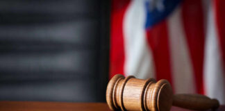 Judicial Misconduct COVER-UP—Dark Secrets Inside Courts A wooden gavel resting on a round base with a blurred American flag in the background
