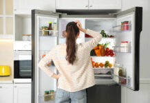 Five-Minute Nutrition Panic Grips America A woman standing in front of an open refrigerator filled with various fruits and vegetables