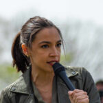 A woman speaking passionately into a microphone at an outdoor event