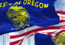 Oregon state flag waving in front of an American flag