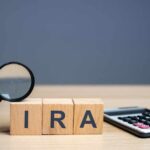 Massive WIN: Trump Unveils Retirement Plan for Americans Magnifying glass and wooden blocks spelling 'IRA' next to a calculator