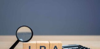 Magnifying glass and wooden blocks spelling 'IRA' next to a calculator
