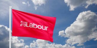 Red flag with 'Labour' logo waving against a cloudy sky