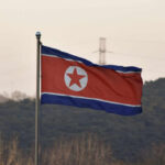 Missile Madness: North Korea Defies UN Rules North Korean flag waving against a mountainous backdrop