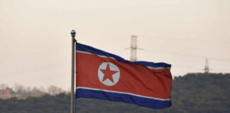 Missile Madness: North Korea Defies UN Rules North Korean flag waving against a mountainous backdrop