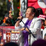Speaker at outdoor rally addressing crowd with microphone
