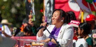 Speaker at outdoor rally addressing crowd with microphone