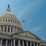 The U.S. Capitol building with an American flag flying against a blue sky