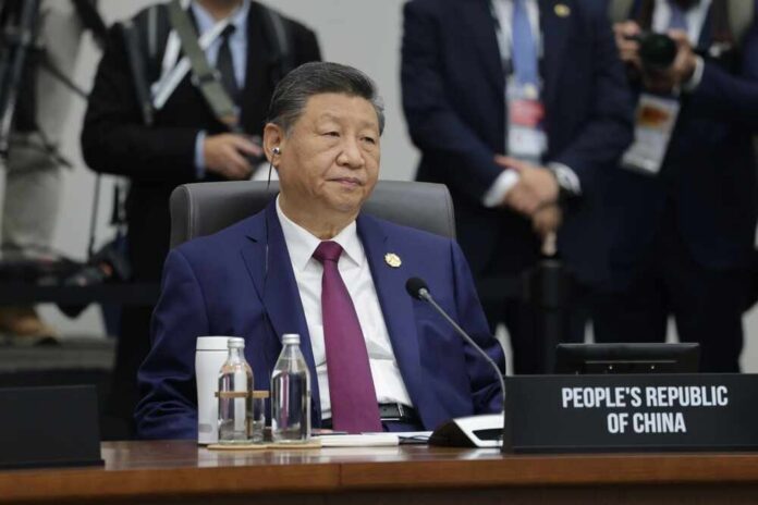 shutterstock_2699228133.jpg A seated leader at a conference table with a nameplate indicating the People's Republic of China