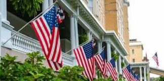 Patriotism Meets HOA Power American flags hanging along a historic building porch