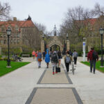 Dorm Predator Still Loose — Parents Revolt Students walking along a pathway on a university campus with historic buildings in the background