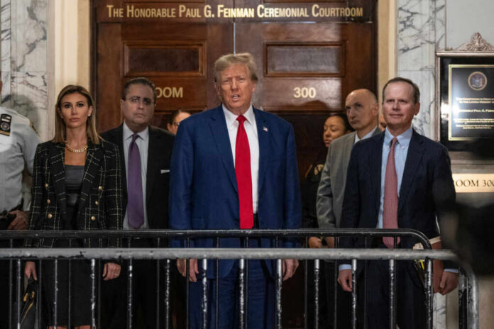 shutterstock2411512549jpg A group of individuals, including a political figure, standing in front of a courtroom entrance