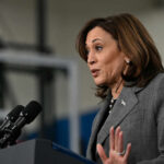 A female politician speaking at a podium with microphones
