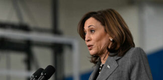 Rule Of Law—or Political Payback? A female politician speaking at a podium with microphones
