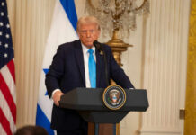 Ally Bombs Capital, Trump Erupts A political figure speaking at a podium with American and Israeli flags in the background