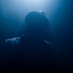 Massive Reward Offered For MS-13 Bosses Silhouetted man in fedora and suit under dramatic blue light