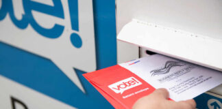 Person placing a mail-in ballot into a voting drop box