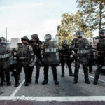 Law enforcement officers in riot gear standing in formation