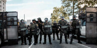 Law enforcement officers in riot gear standing in formation