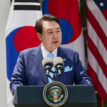 Did A President Try Manufacturing War? A government official delivering a speech at a podium with flags in the background