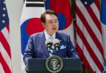 Did A President Try Manufacturing War? A government official delivering a speech at a podium with flags in the background