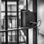 Close-up of a jail cell lock with a key hanging