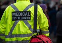 Teen Killed After Graduation—Families Demand Answers Medical first responder wearing a bright yellow jacket and carrying a red bag