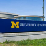 University of Michigan campus sign in front of modern buildings