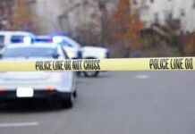 Teen Couple Tied To Family Massacre Police tape cordons off a street with patrol cars in the background