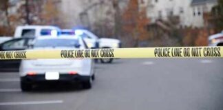 Teen Couple Tied To Family Massacre Police tape cordons off a street with patrol cars in the background
