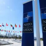 NATO Rift Erupts Over Trump Demands NATO flags displayed in front of the NATO headquarters under a clear blue sky