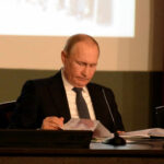 A leader in formal attire reading documents during a meeting