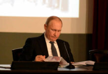 A leader in formal attire reading documents during a meeting