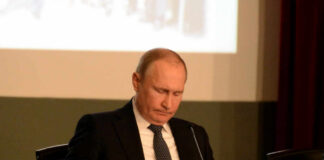 A leader in formal attire reading documents during a meeting