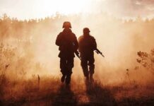 Iran Missiles Kill Americans — War Just Got Real Two soldiers walking through a smoky field at sunset
