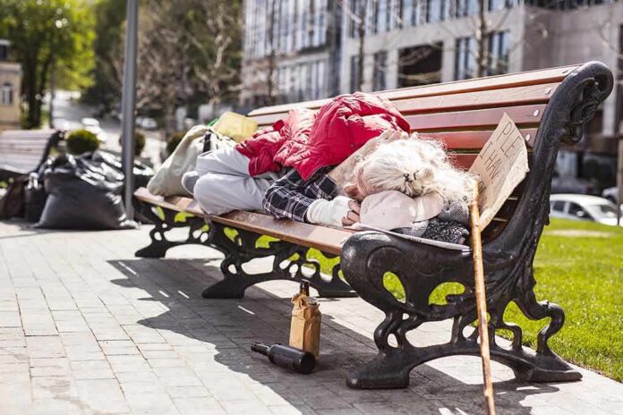 Person sleeping on a park bench with belongings