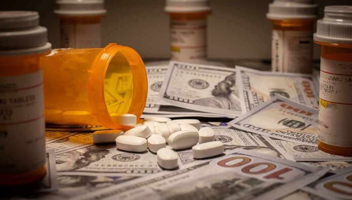 shutterstock_1270738678 Prescription pill bottle and white tablets on scattered US dollar bills