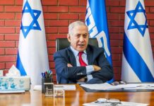 Mayor Plots Netanyahu Arrest man in suit seated at desk with Israeli flags
