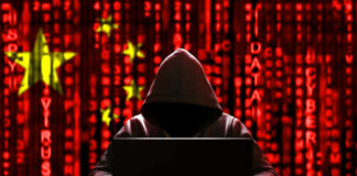 Declassified Files Detail Massive Voter Database A hooded figure sitting in front of a laptop with a red digital background