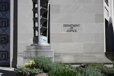 Department of Justice building exterior with stone facade and plants