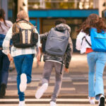 Group of children walking together with backpacks in an urban area