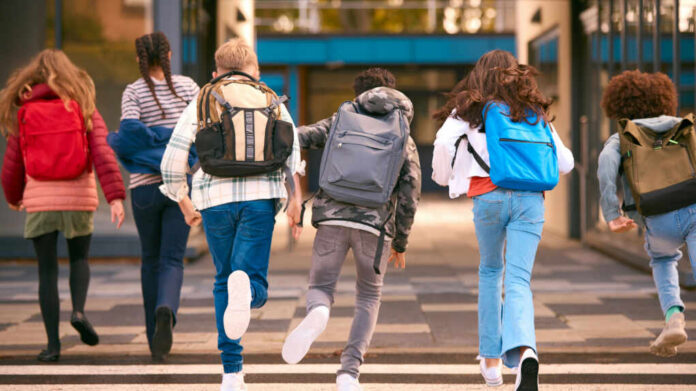 shutterstock_2394500109-1 Group of children walking together with backpacks in an urban area